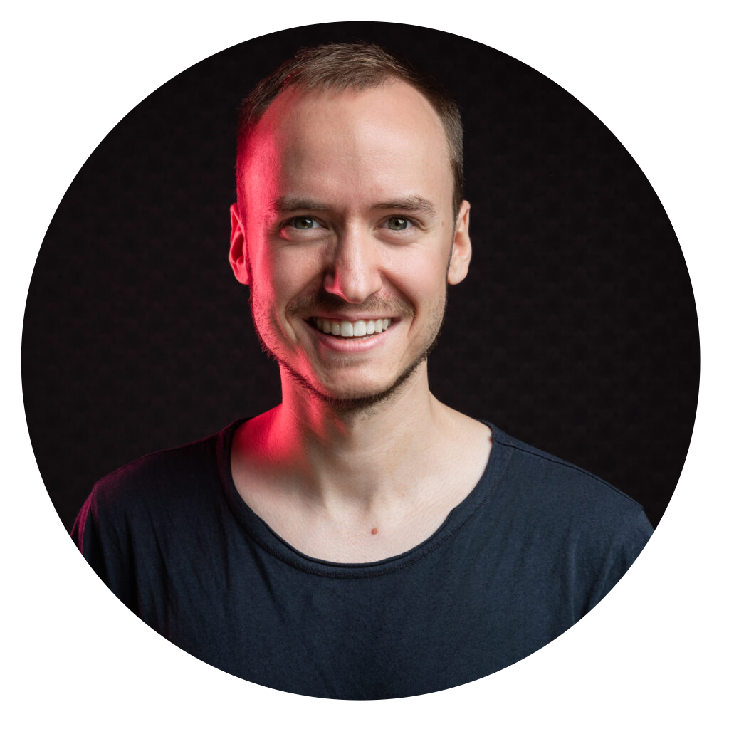 Porträtfoto eines lächelnden Mannes mit schwarzem T-Shirt und roter Lichtkante vor dunklem Hintergrund